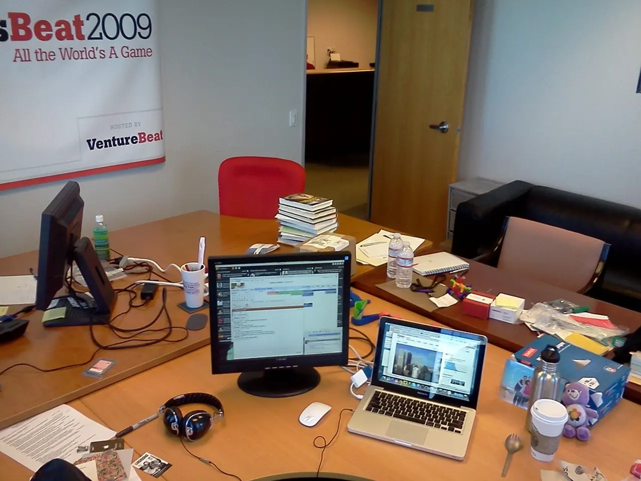 As we can see in the image there is a white color wall, door, banner, sofa and table. On table...