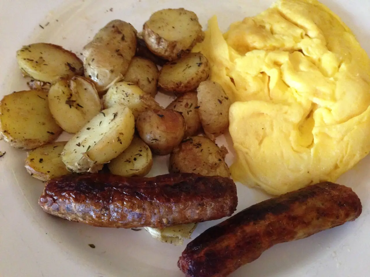 In this image there is a plate in which there is some food. At the bottom there are two hot dogs....