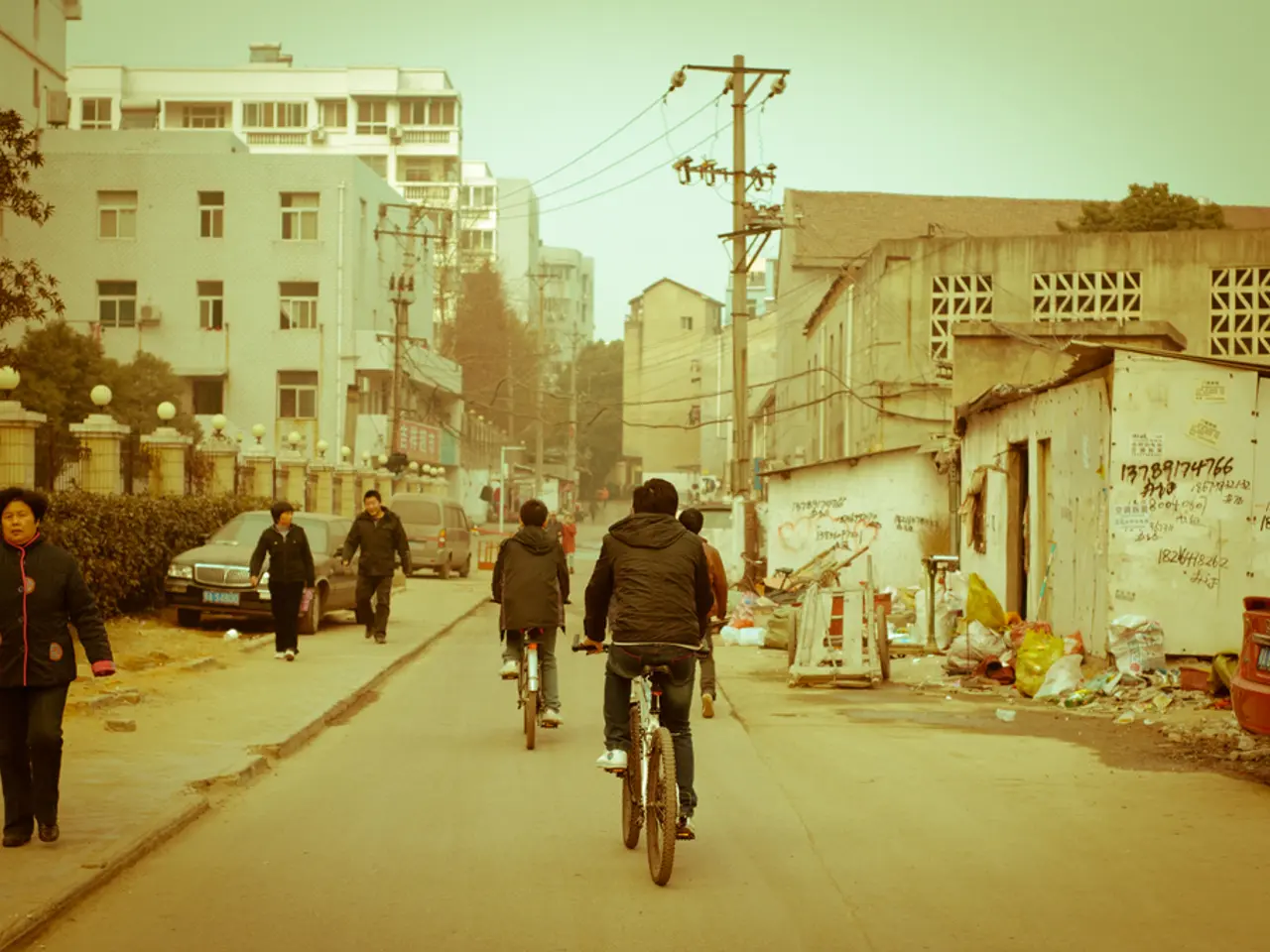 In the image there are few people walking and some of them are riding cycle there are also current...