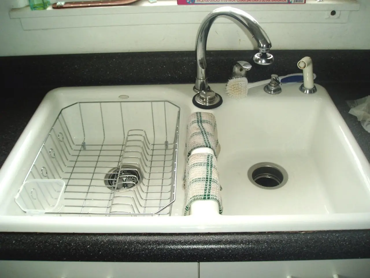 In this picture I see the white color sink in front and I see the clothes on it and I see the taps...