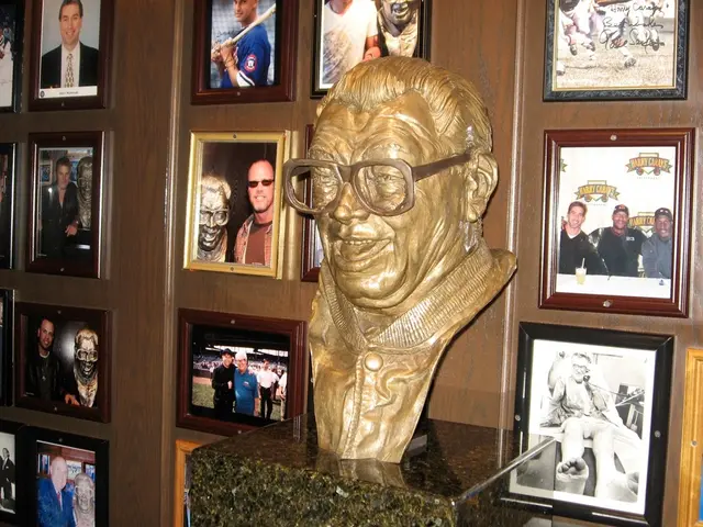 There is a sculpture on the surface of stone. Behind it, photographs are attached to the wall.