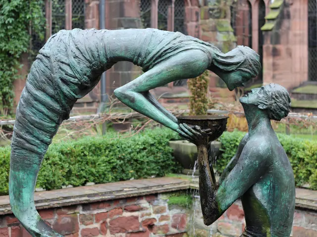 In this image there is a sculpture of a man and a woman holding the same bowl. In the background...