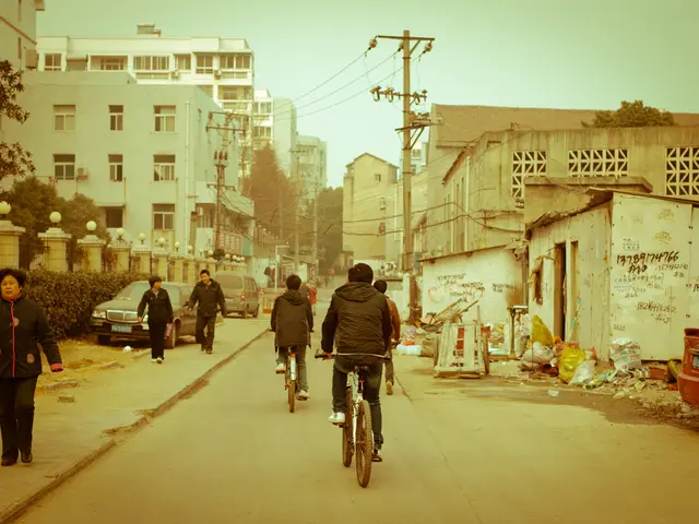 In the image there are few people walking and some of them are riding cycle there are also current...