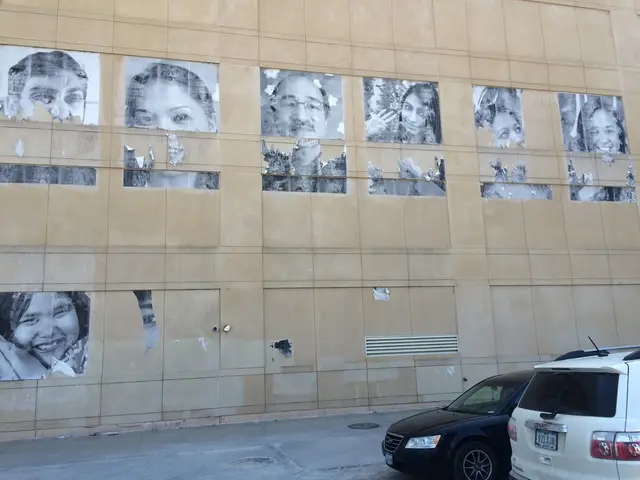 This is the picture of a building. In this image there are cars on the road and there are manholes...